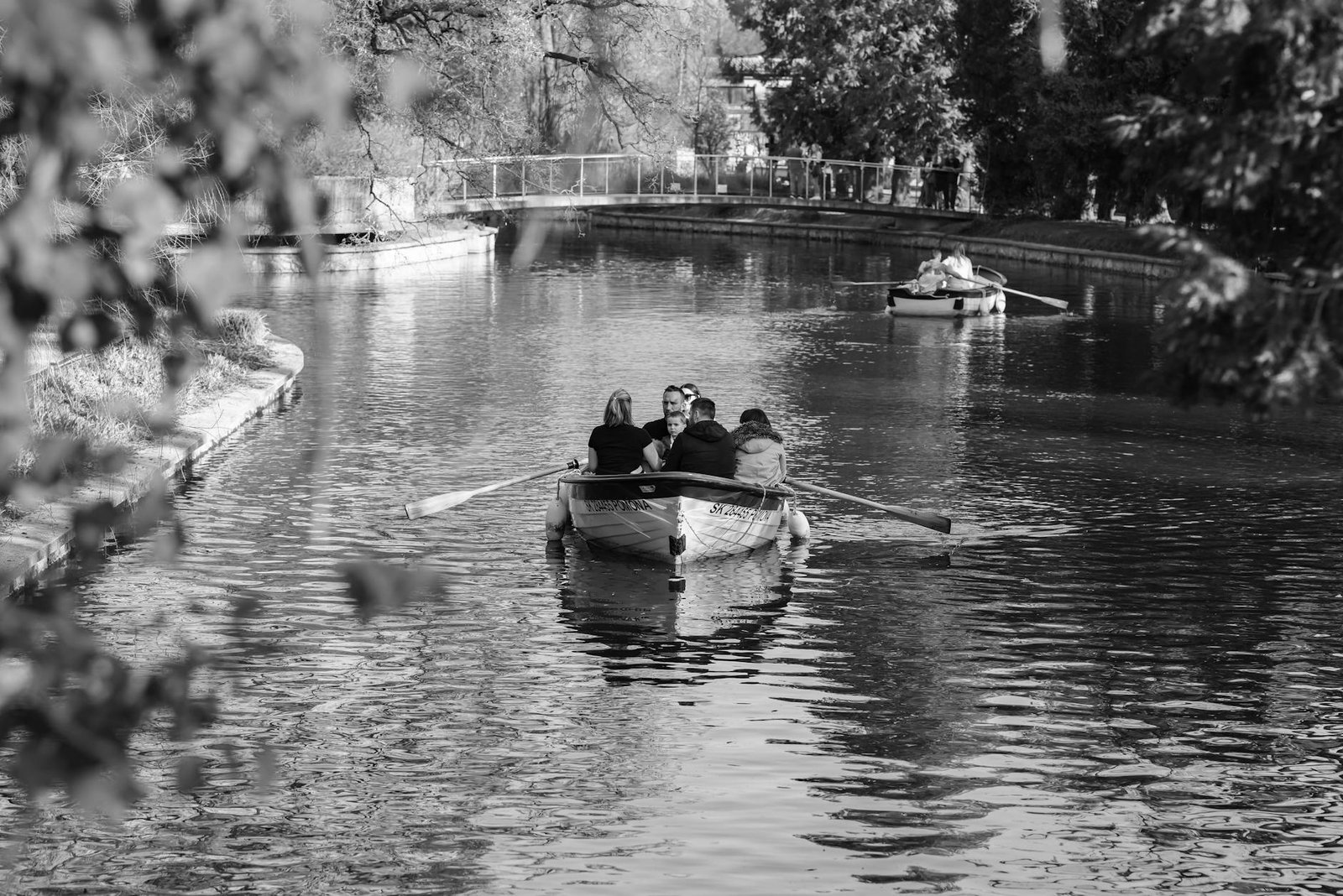 Couples enjoying a tranquil boat ride on a peaceful canal in Zagreb, surrounded by lush nature.