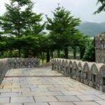 Explore the historic stone pathway leading to Kumbhalgarh Fort's lush greenery.