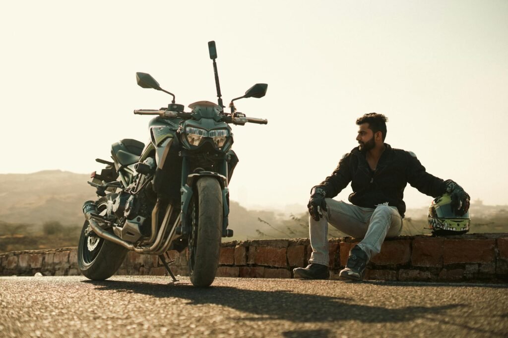 Man sitting on brick wall with helmet and motorbike, Jodhpur view.