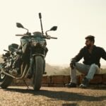 Man sitting on brick wall with helmet and motorbike, Jodhpur view.